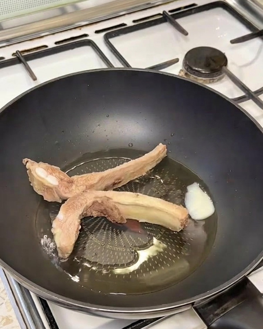 Goldbraun angebratene Schweinerippchen brutzeln im geschmolzenen Schmalz.