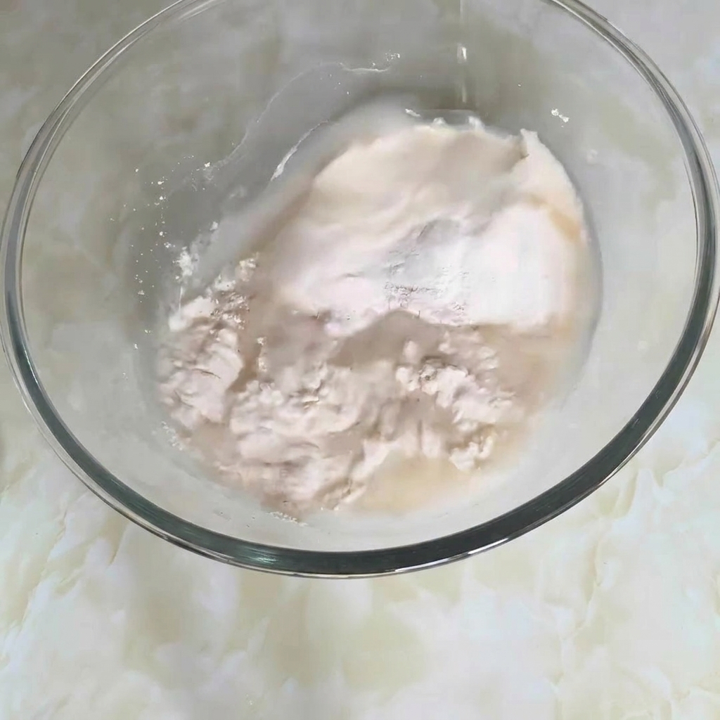 Eine Rührschüssel mit Mehl, Wasser und anderen Zutaten, die zu einem Teig verrührt werden.