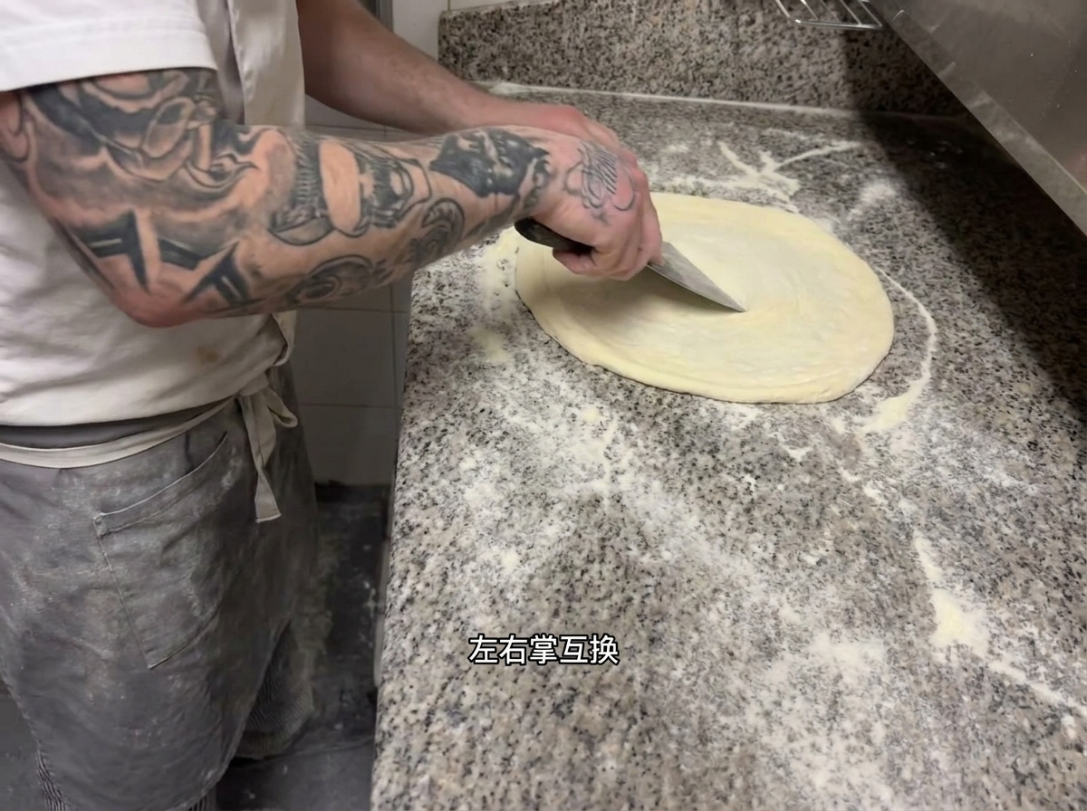 Ein Koch bei der rhythmischen Dehntechnik des Pizzateigs.