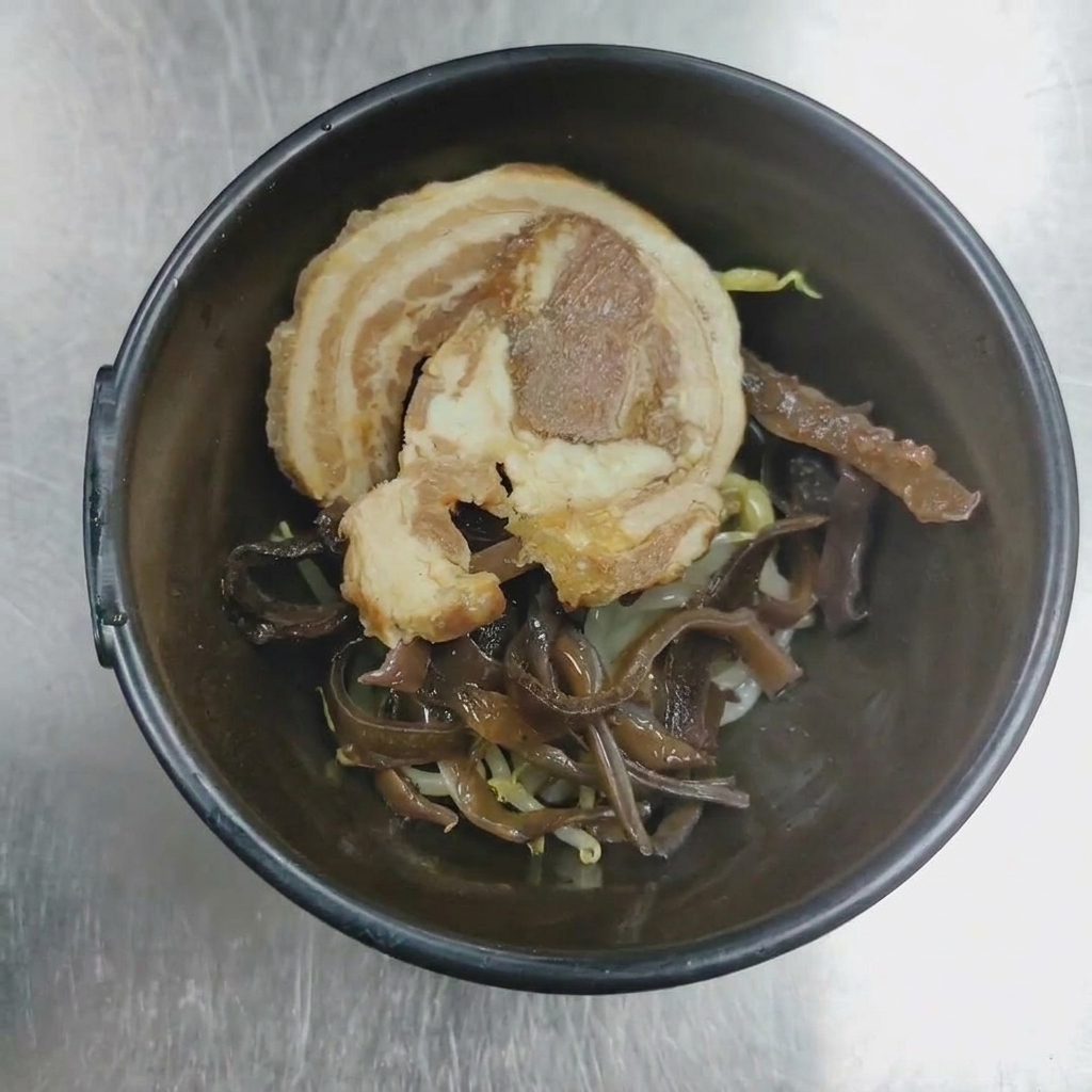 Nahaufnahme einer Servierschüssel mit gerolltem Chashu-Schweinefleisch und Mu-Err-Pilzen, bereit zum Anrichten.