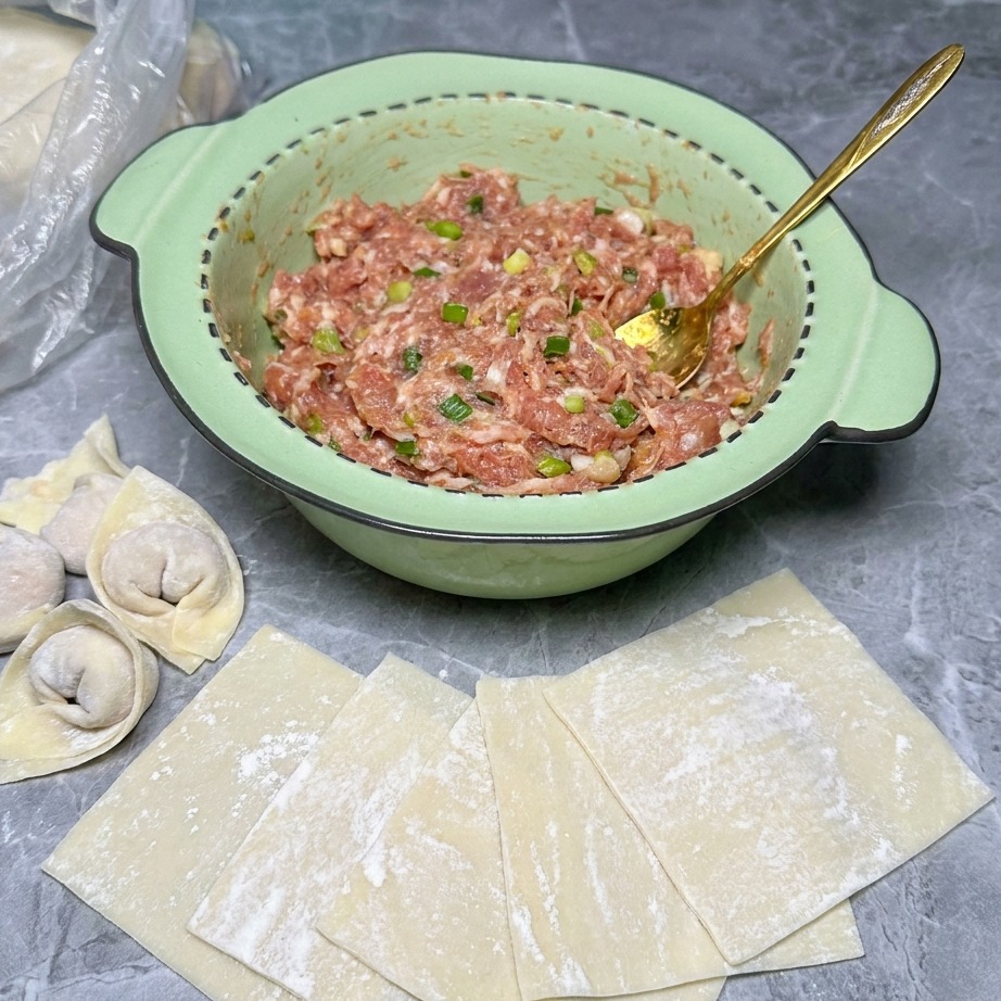 Ein kleiner Klecks Fleischfüllung in der Mitte eines Wonton-Teigblatts.