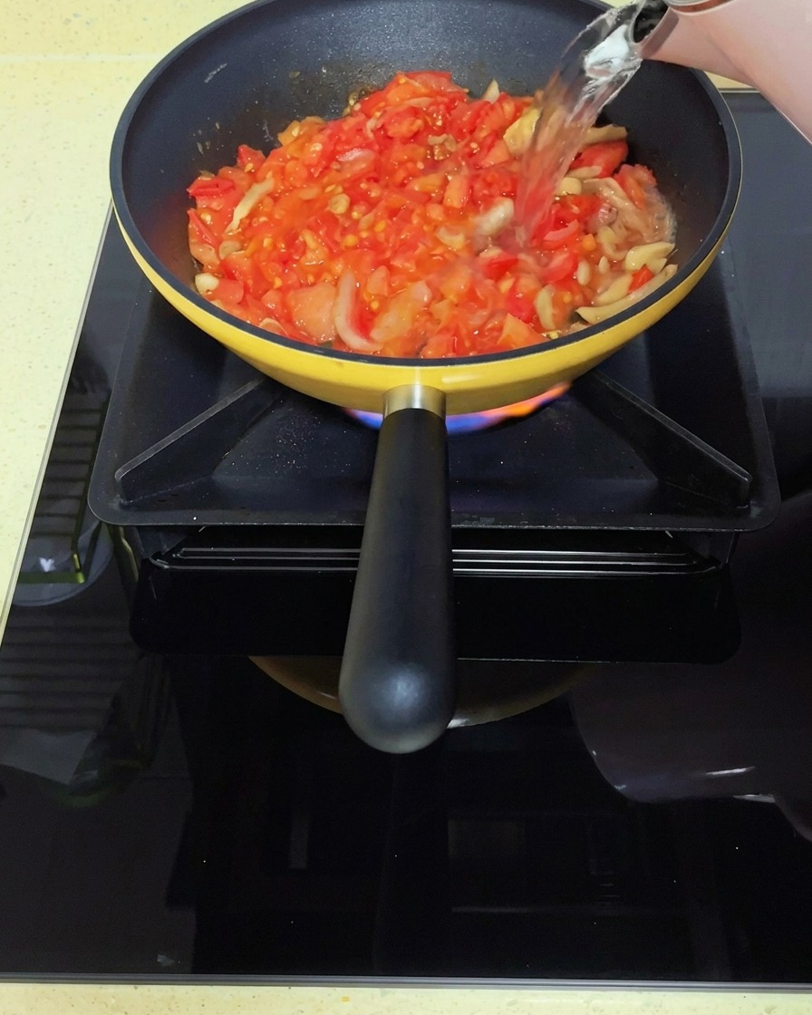 Kochendes Wasser wird in die Tomaten-Senfgrün-Mischung gegossen.