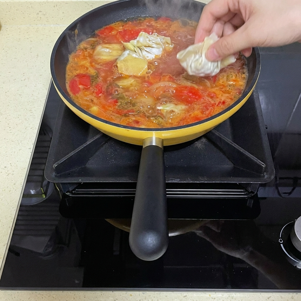 Rohe, gefaltete Wontons werden in die siedende Tomatenbrühe gegeben.
