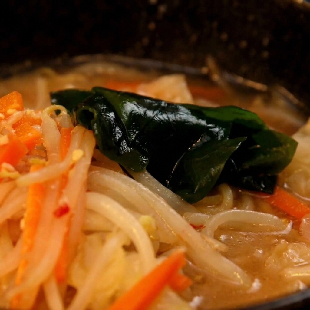 Gekochte Ramen-Nudeln werden aus dem Topf in die vorbereitete Miso-Suppenschüssel gegeben.