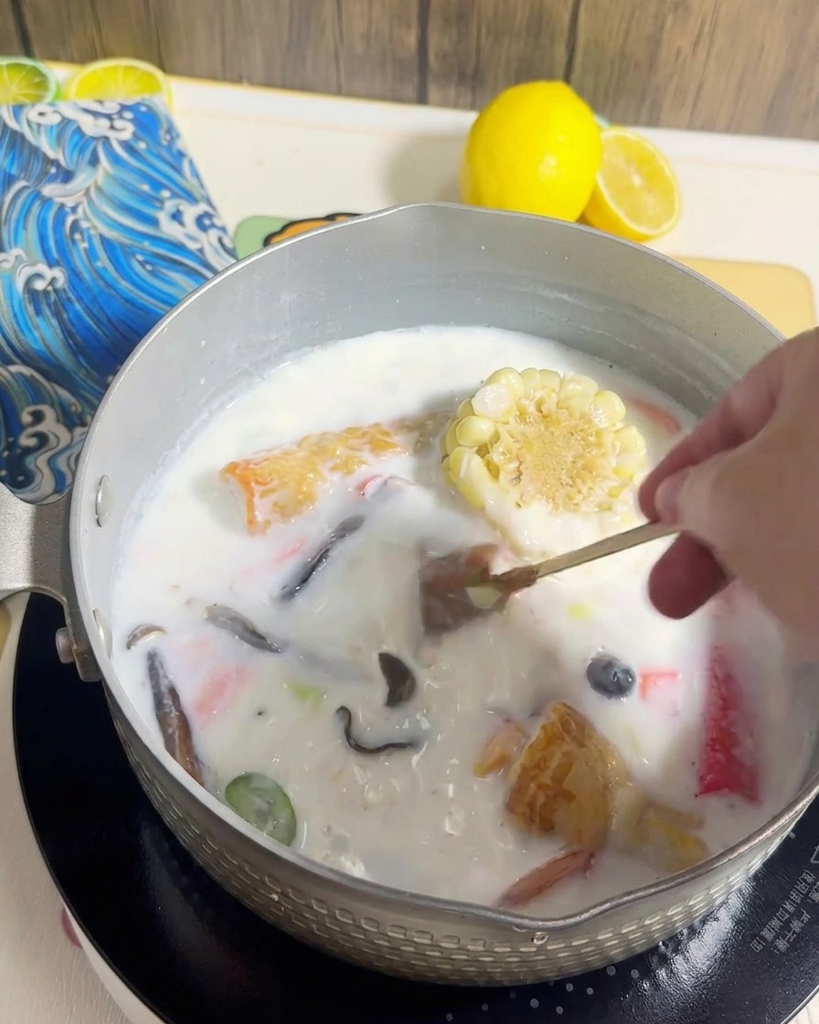 Ramen-Nudeln werden in den Topf mit der cremigen Brühe und den Zutaten gegeben.