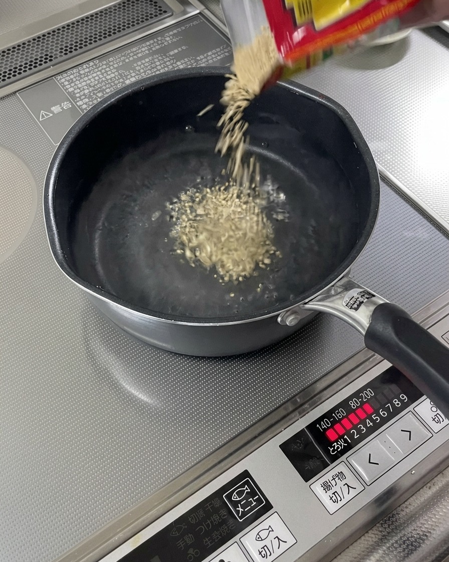 Geröstete Sesamsamen fallen in eine siedende Flüssigkeit.