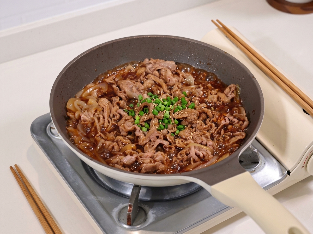 Rindfleisch und Zwiebeln köcheln in einer glänzenden, dunklen Sojasauce.