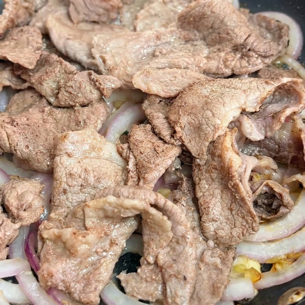 Dunkle Teriyaki-Sauce wird in die Pfanne über das Rindfleisch gegossen.