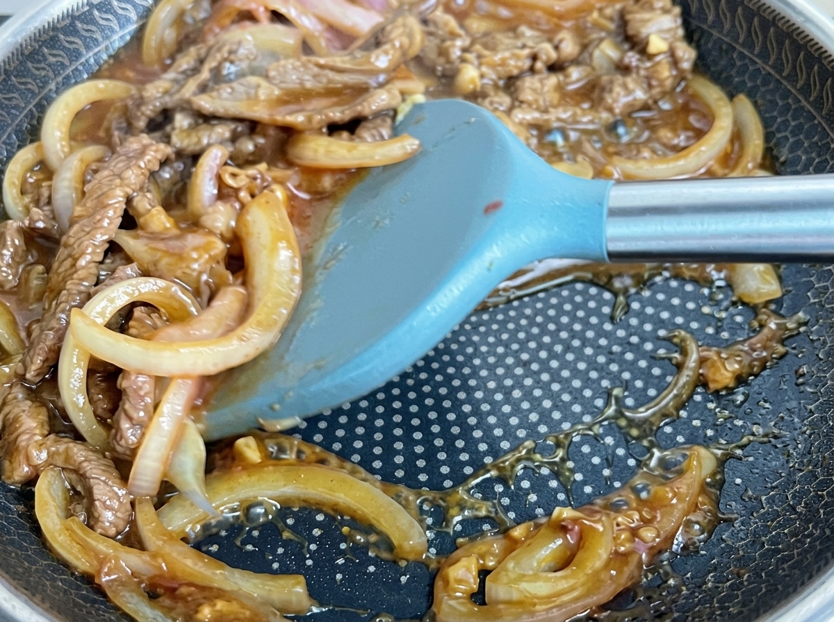 Fleisch und Zwiebeln kochen in der Blubbernden dunklen Sauce.