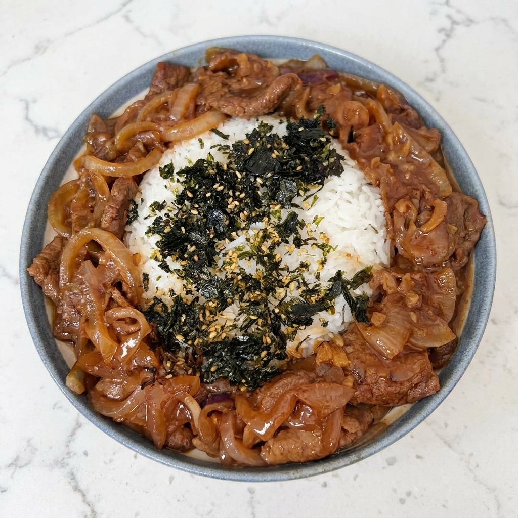 Nahaufnahme einer Reis-Bowl, die mit zerbröseltem Nori-Seetang und geröstetem Sesam bestreut wird.