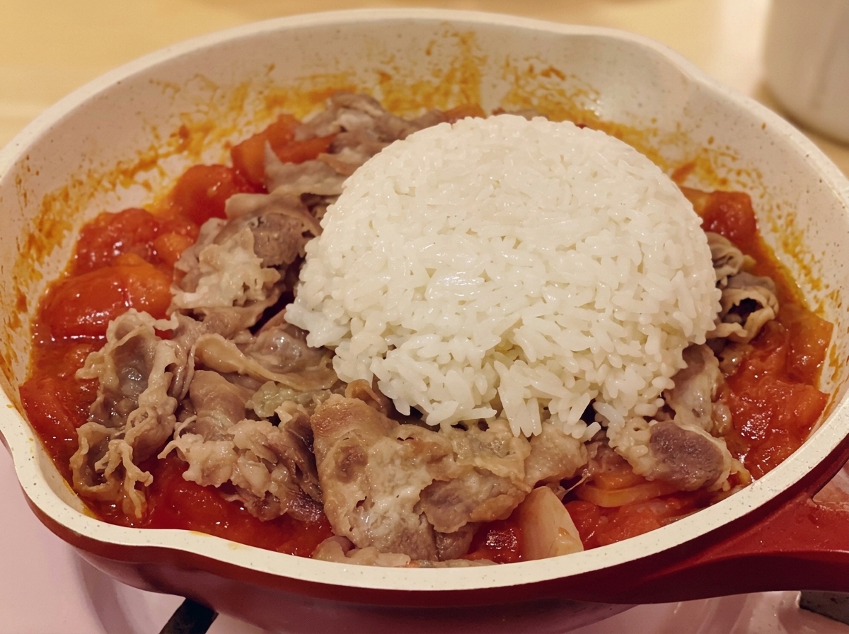 Eine Portion weißer Reis auf der Rindfleisch-Tomaten-Mischung in der Pfanne.