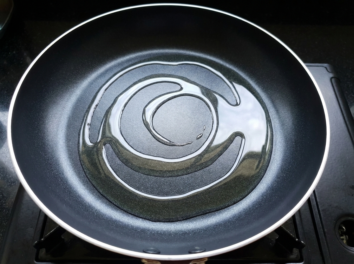 Marinierte Hähnchenstücke werden in einer heißen, geölten Pfanne angebraten.