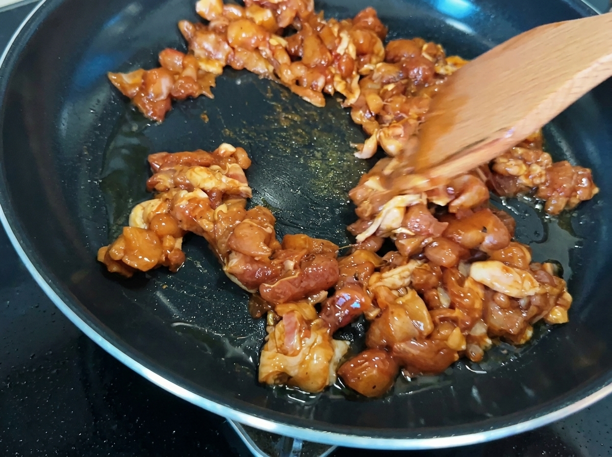 Hähnchenstücke in der Pfanne zeigen eine goldbraune Karamellisierung.