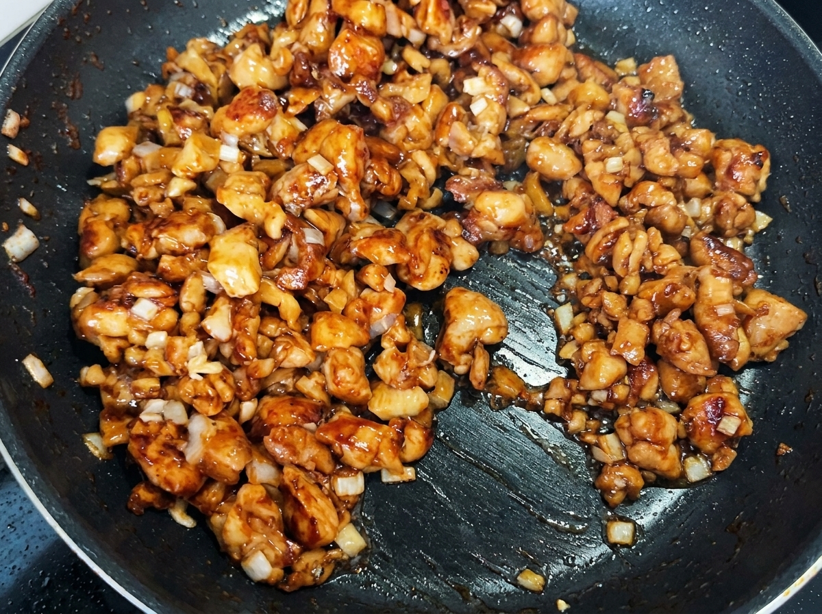 Gewürfelter Senfkohl wird mit dem Hähnchen und den Zwiebeln in der Pfanne vermischt.