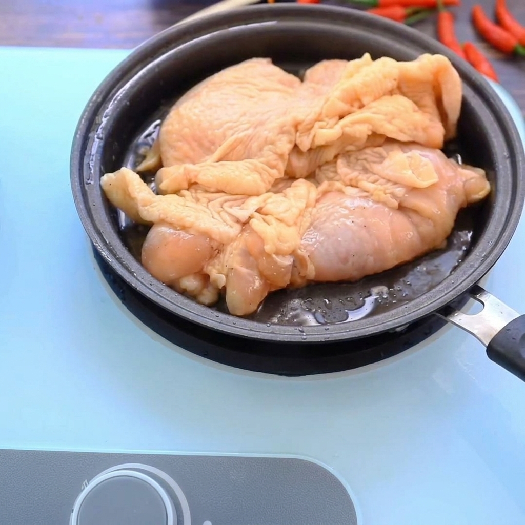 Hähnchenschenkel braten in einer heißen Pfanne und erhalten eine goldbraune Kruste.