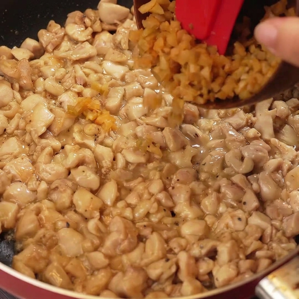 Fein gehackter Senfkohl und weiße Zwiebelstücke werden zu einer Pfanne mit gebratenem, goldbraunem Hähnchen hinzugefügt.