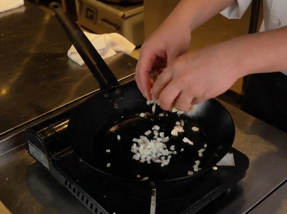 Gehacktes Hähnchen und Knorpel werden zu den Zwiebeln in die heiße Pfanne gegeben.