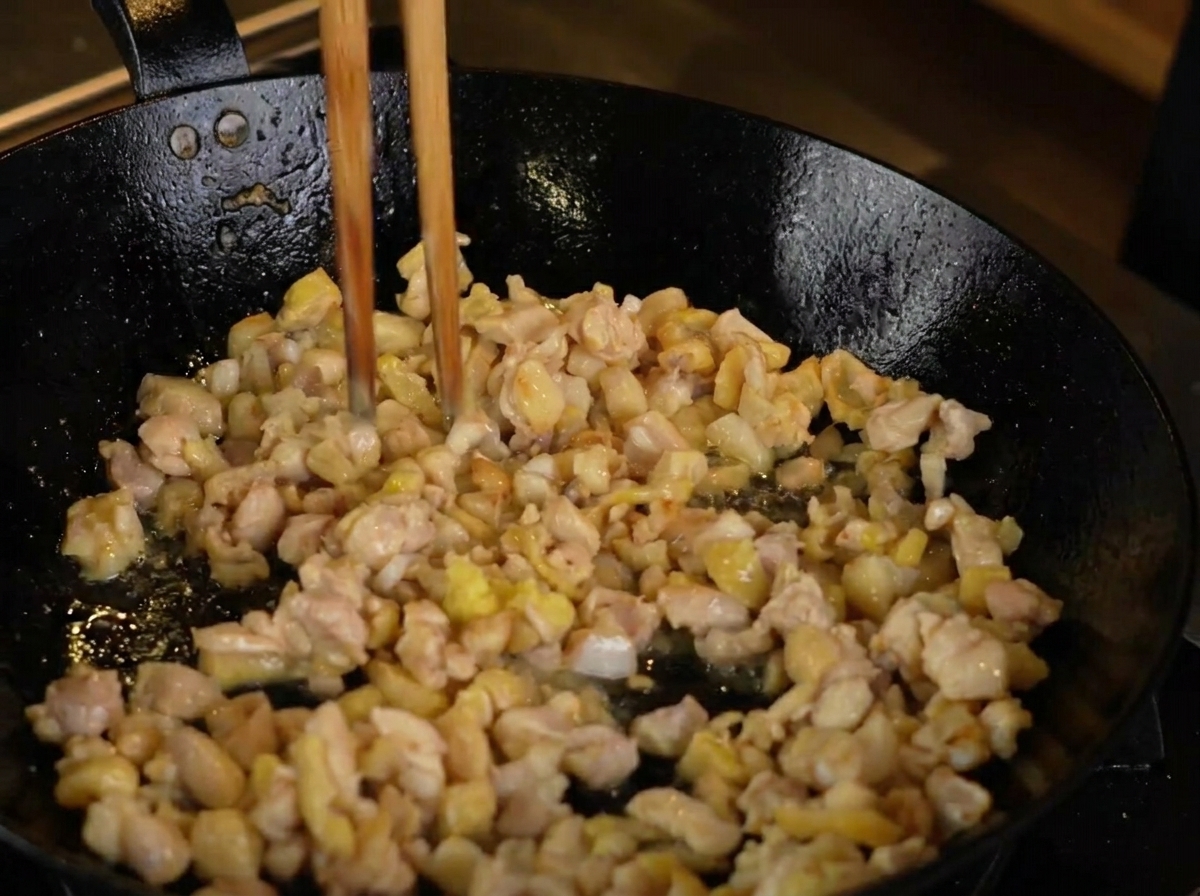 Geriebener Ingwer wird zum anbratenen Fleisch gegeben.