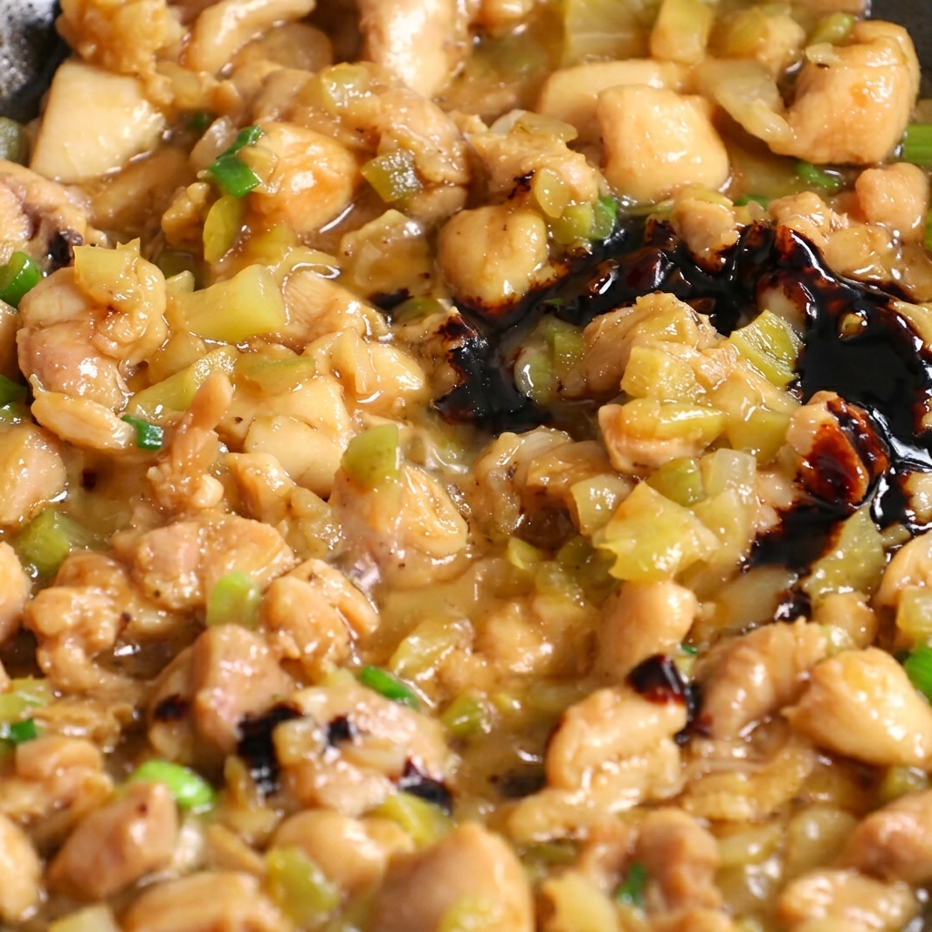 Dunkle Sojasauce wird in eine Pfanne mit der Pfannengericht-Mischung aus Hähnchen und Gemüse gegossen.