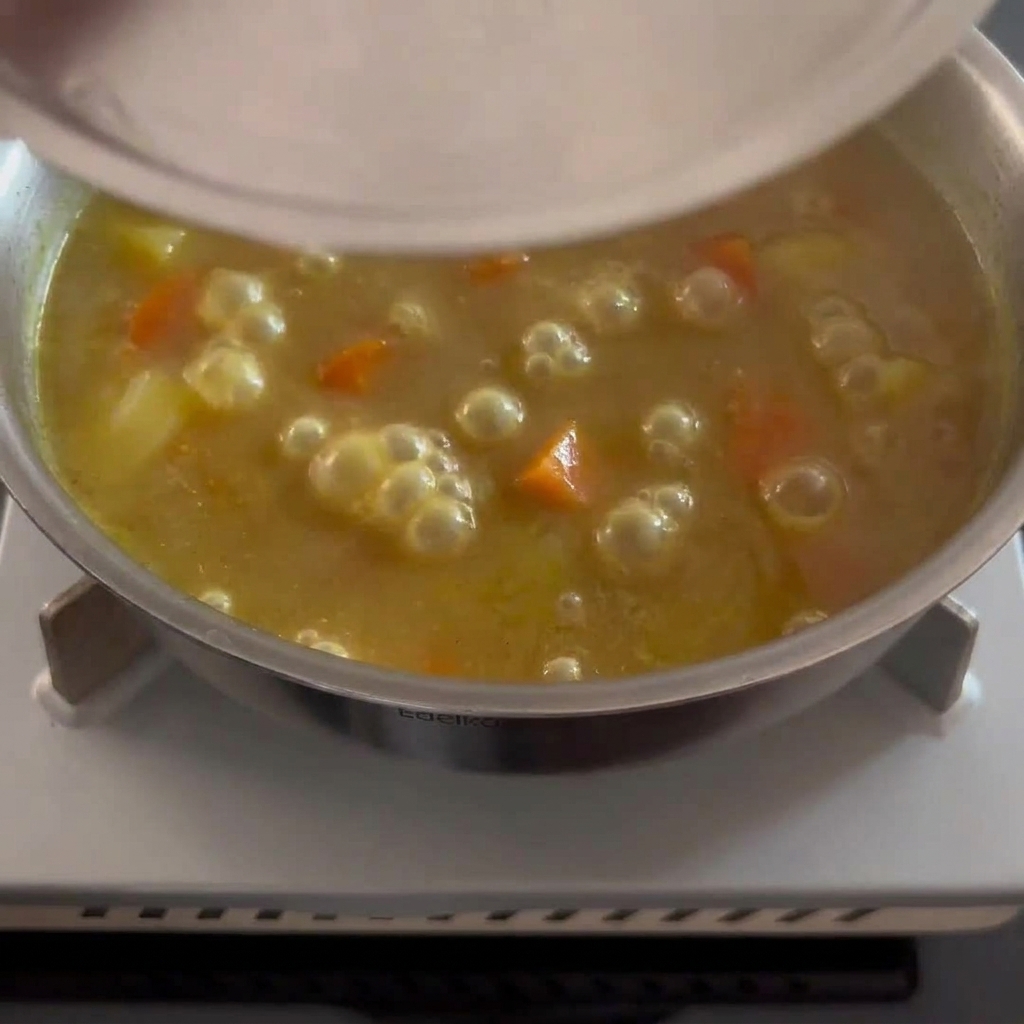 Die Currysoße köchelt fertig mit sichtbaren Gemüsestücken.