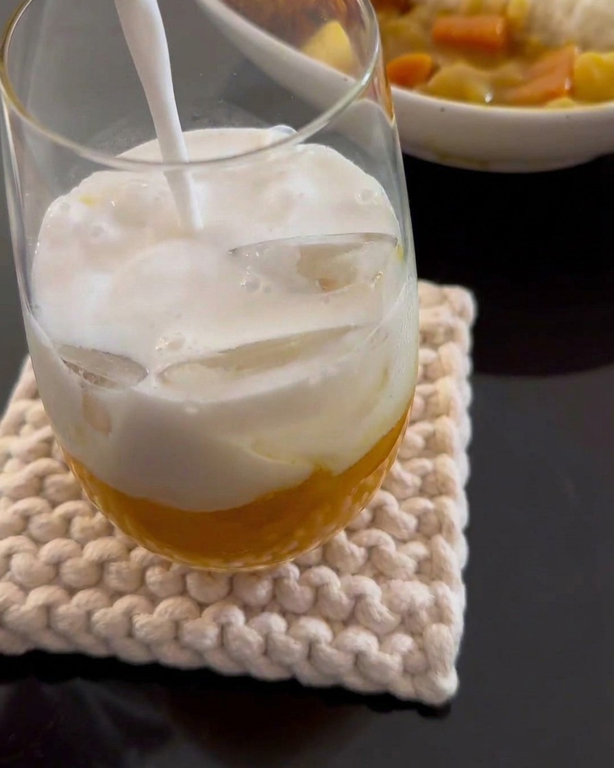 Kokosmilch wird in ein Glas mit Mangopüree und Eis gegossen.