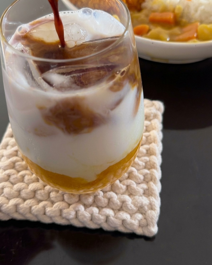 Ein Espresso wird über ein geschichtetes Getränk aus Mango, Eis und Kokosmilch gegossen.