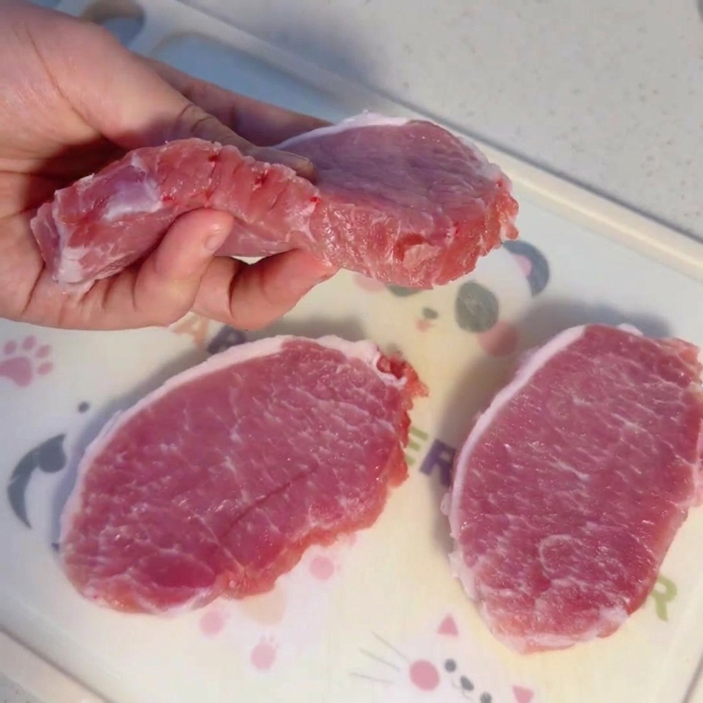 Dicke Scheiben rohes Schweinefilet auf einem Schneidebrett.
