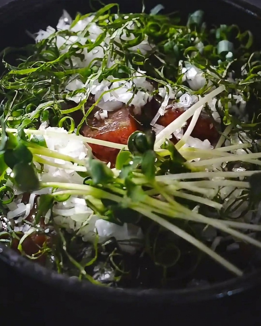 Ein rohes Eigelb wird in der Mitte der garnierten Thunfisch-Reis-Bowl platziert.