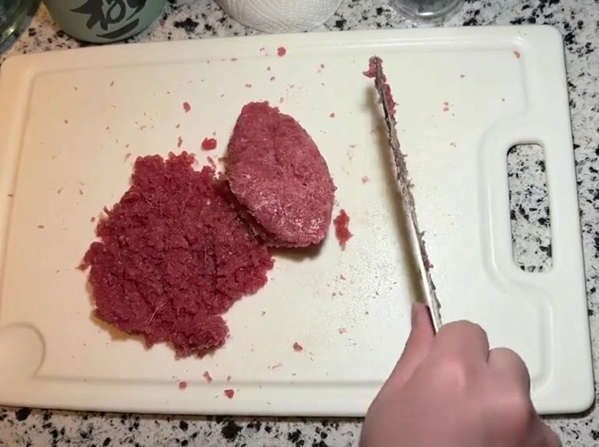 Ein Messer vermengt die mit Mayonnaise versehene Thunfischpaste mit dem restlichen gehackten Thunfisch.