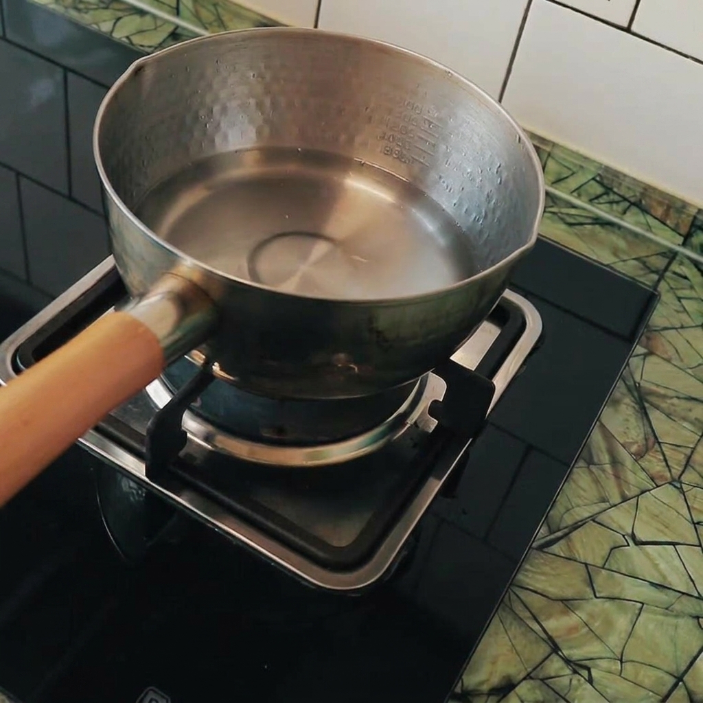 Tofuwürfel werden in einen Topf mit kochendem Wasser gegeben.