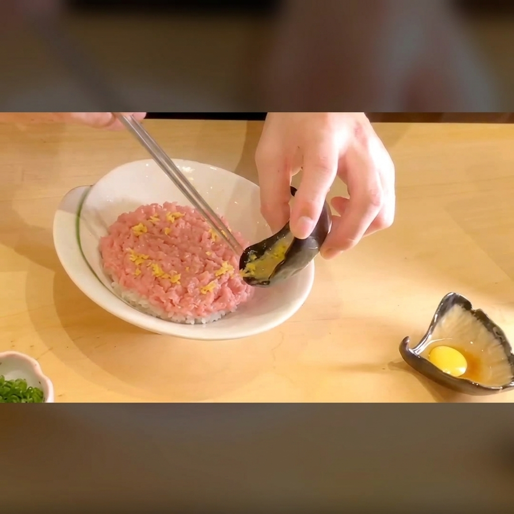 Eingelegter gelber Rettich wird als Kontrast auf den Thunfisch gelegt.