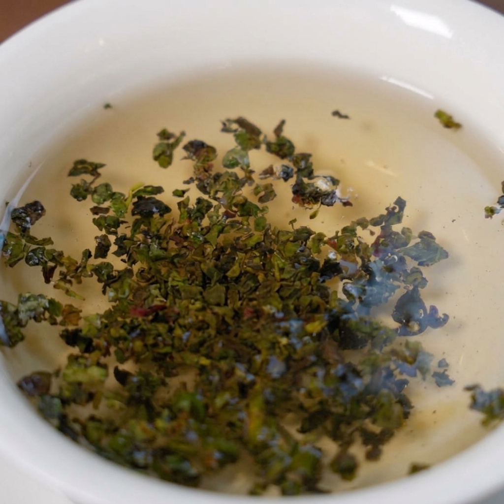 Grüne Tieguanyin-Teeblätter, die in einer weißen Schale mit heißem Wasser aufgehen.