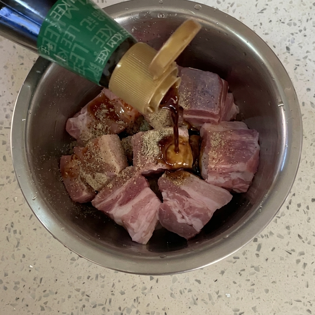 Sojasauce wird über den gewürzten Schweinebauch gegossen.