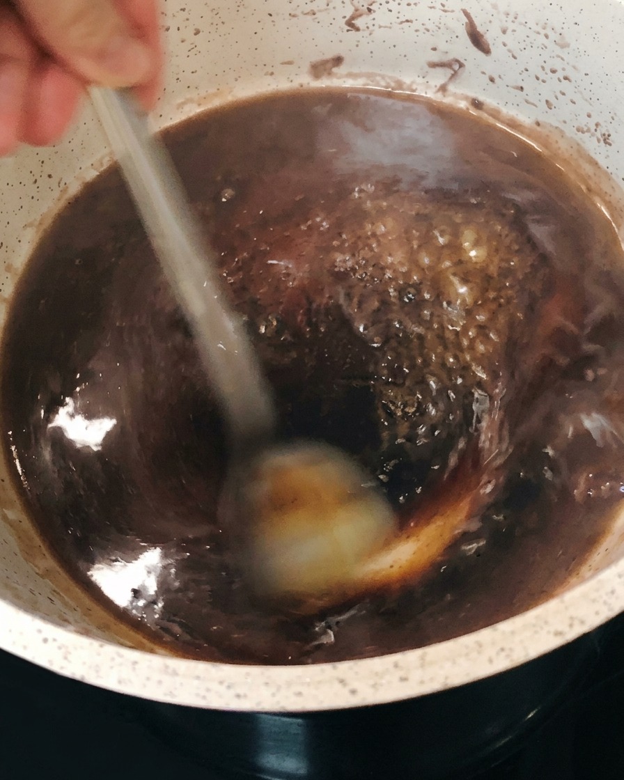 Die dunkle Rotweinreduktion, die im Topf blubbert und andickt, während umgerührt wirdcite: 1.