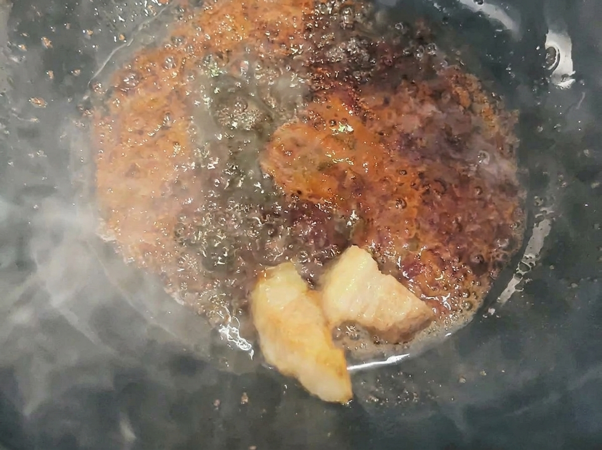Fleischwürfel werden im Wok mit flüssigem Karamell geschwenkt und überzogen.