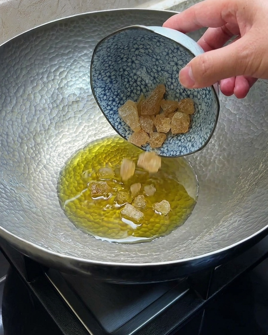 In einer Metallpfanne schmelzender und karamellisierender Kandiszucker in heißem Öl.