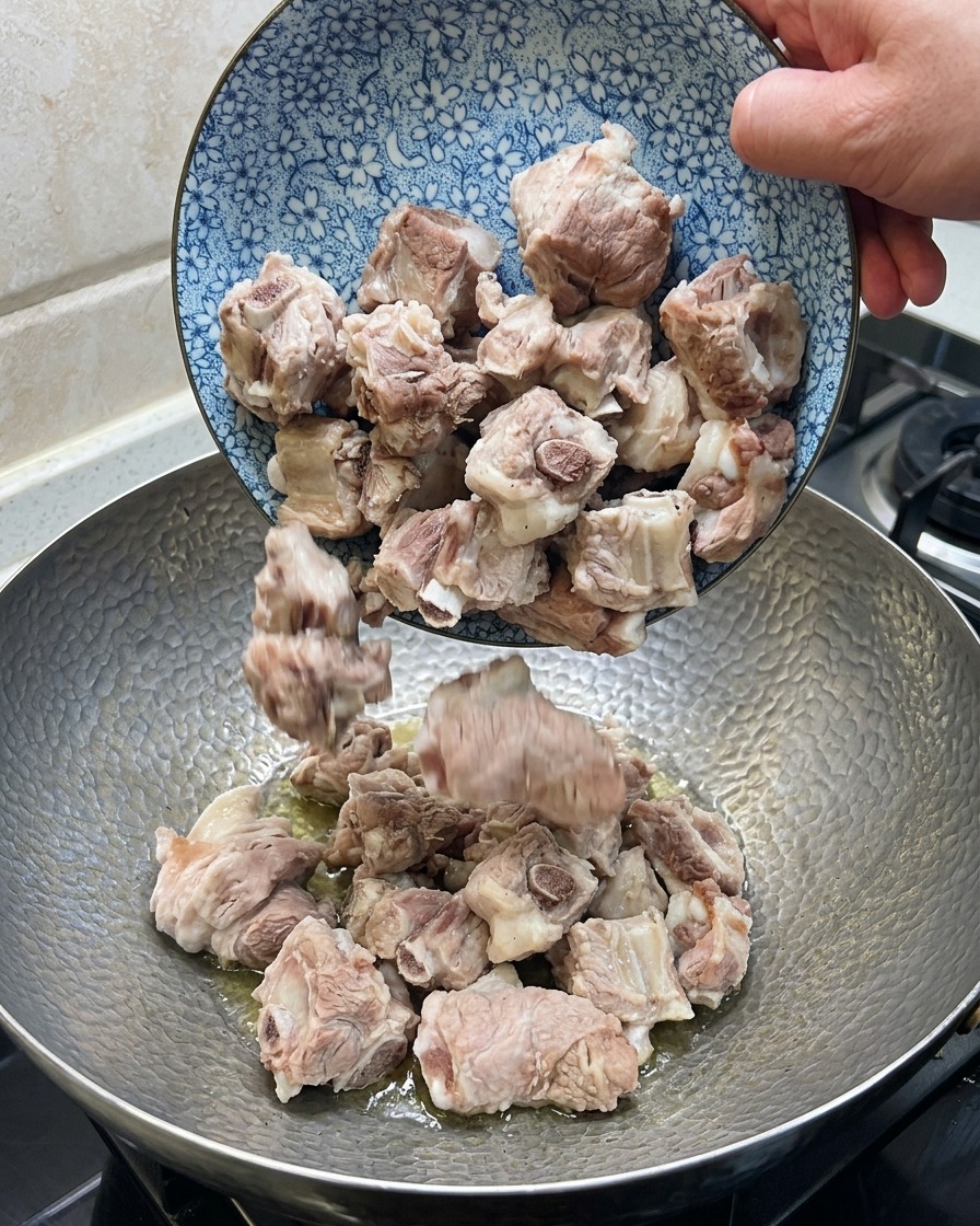 Schweinerippchen werden im Wok mit Ingwer, Sternanis und getrocknetem Chili verrührt.