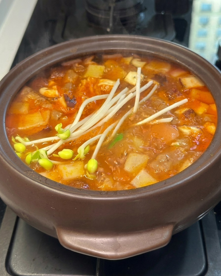 Frische Sojasprossen auf der Oberfläche eines brodelnden koreanischen Steintopfeintopfs.