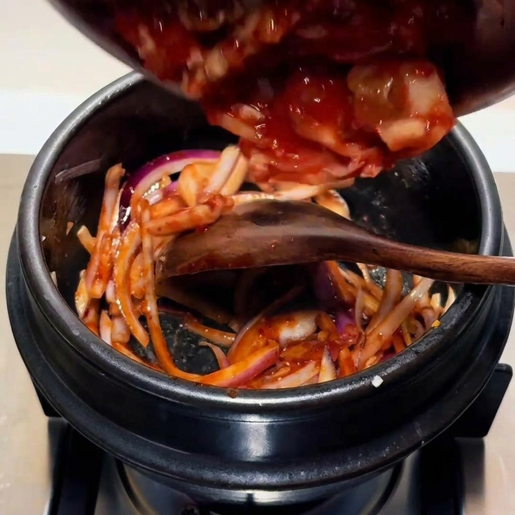 Gehackter Kimchi wird in den Topf zur Zwiebel-Saucen-Basis gegeben.