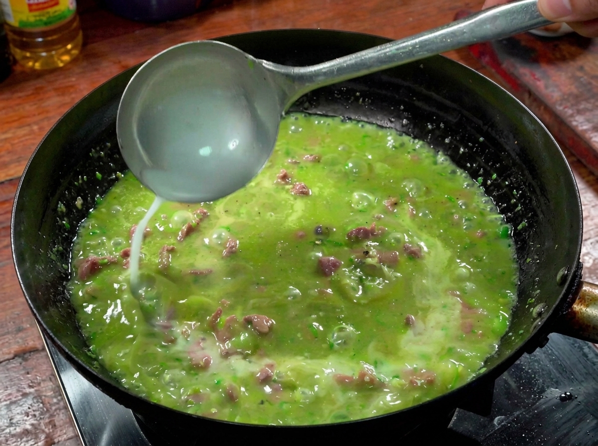 Eine Kelle, die Stärkewasser in die sprudelnde Rindfleisch-Chili-Sauce im Wok gießt.