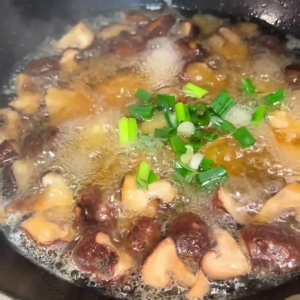 Gehackte Frühlingszwiebeln werden in einen köchelnden Topf mit Pilz-Tofu-Suppe gestreut.