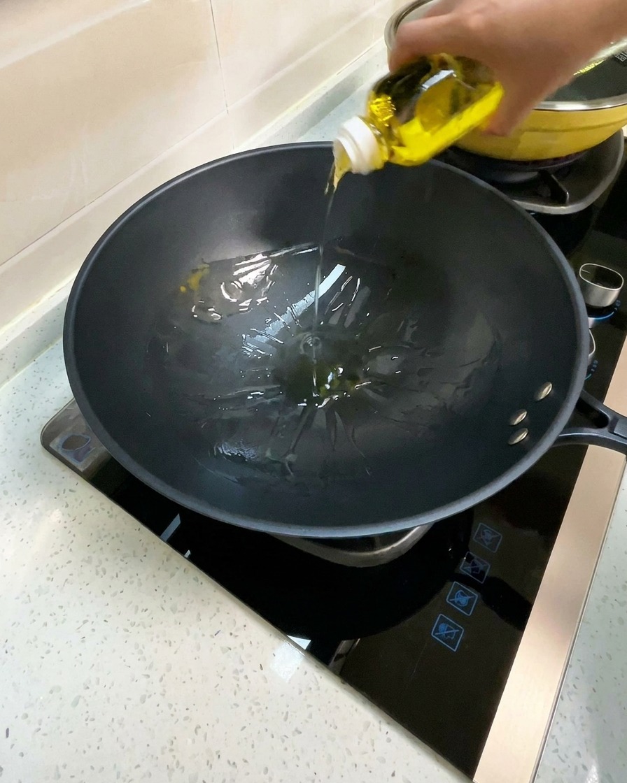 Speiseöl wird in einen vorgeheizten schwarzen Wok gegossen.