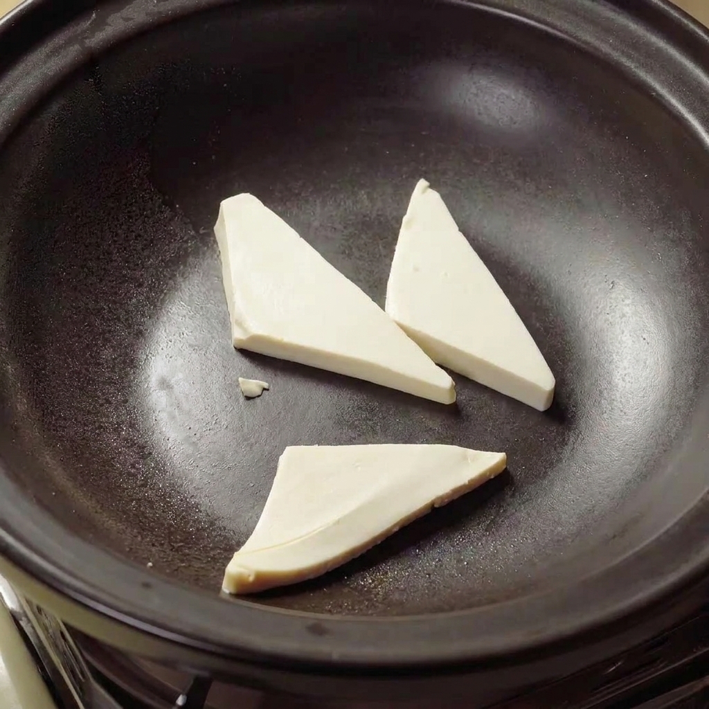 Tofu-Dreiecke, die in heißem Öl in einem Tontopf goldbraun gebraten werden.