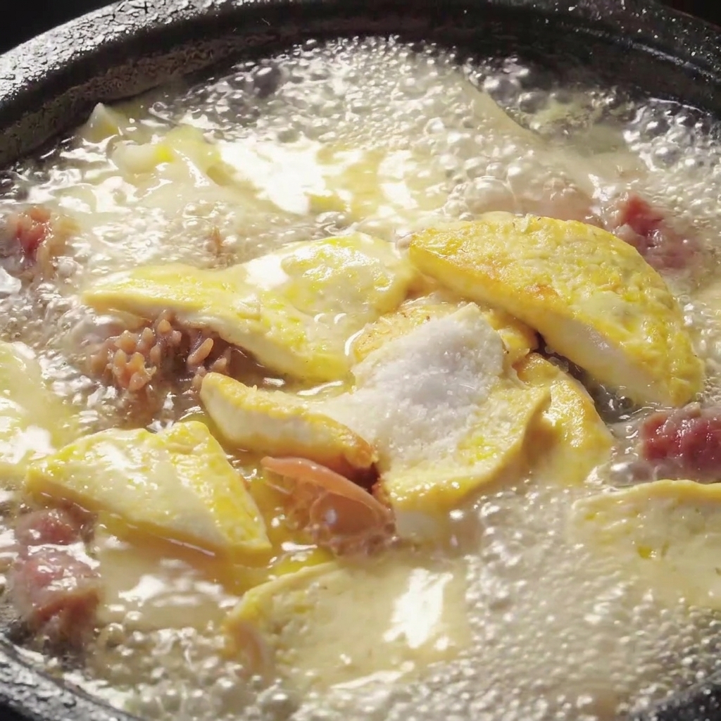 Gewürze werden in einen köchelnden Topf mit Pilz-Tofu-Suppe eingerührt.
