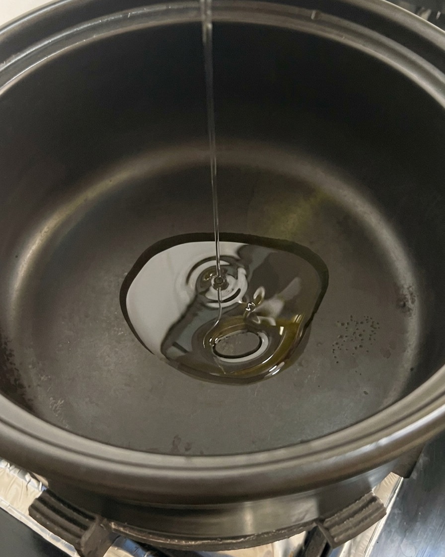 In Scheiben geschnittene Champignons werden in einen schwarzen Topf mit heißem Speiseöl gegeben.