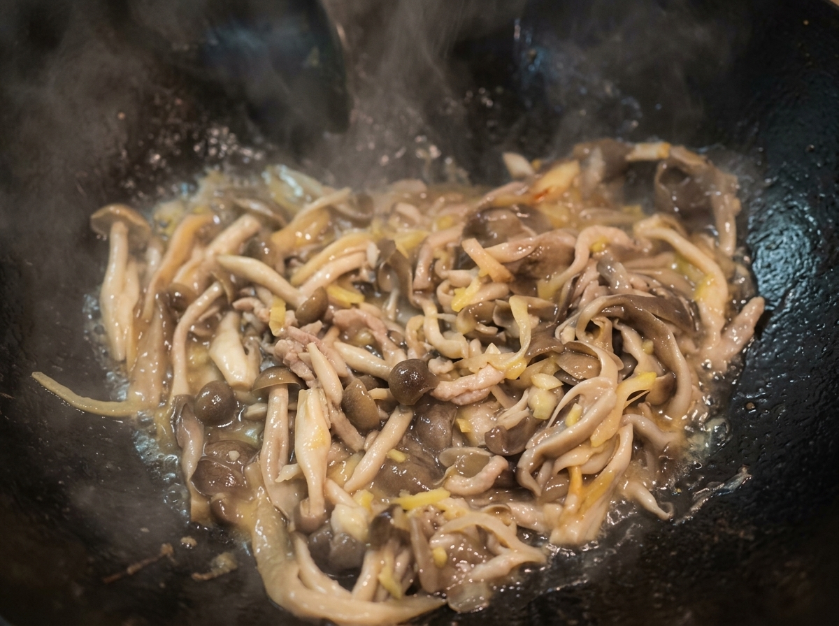 Wasser kocht in einem Wok mit angebratenen Pilzen und bildet eine leichte Brühe.