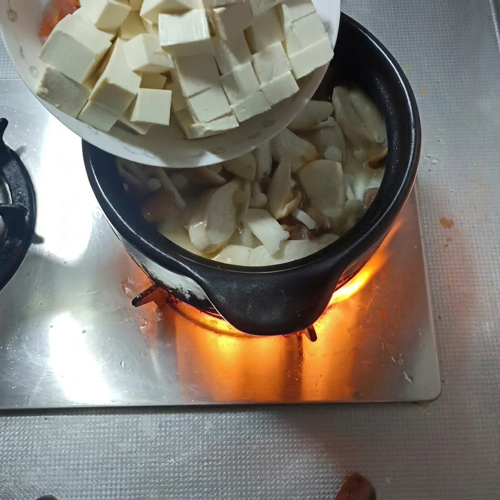 Tofuwürfel und Karottenscheiben werden in die Pilzsuppe gegeben.