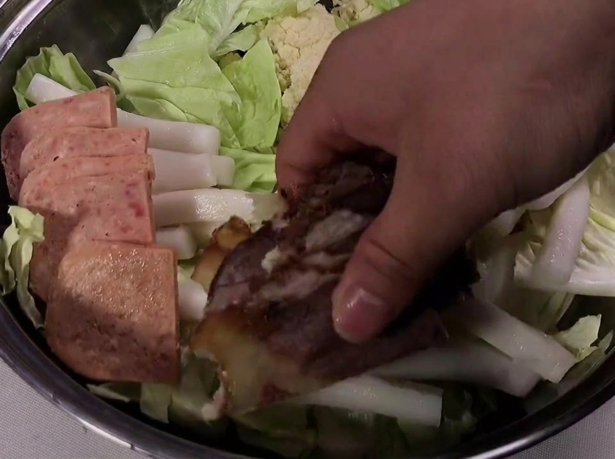 Scheiben von Spam, Rindfleisch und Wurst sind ordentlich am Rand arrangiert.