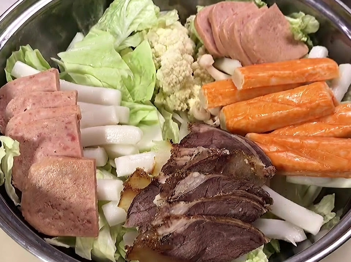 Fischfrikadellen und Garnelen liegen oben auf den anderen Zutaten.