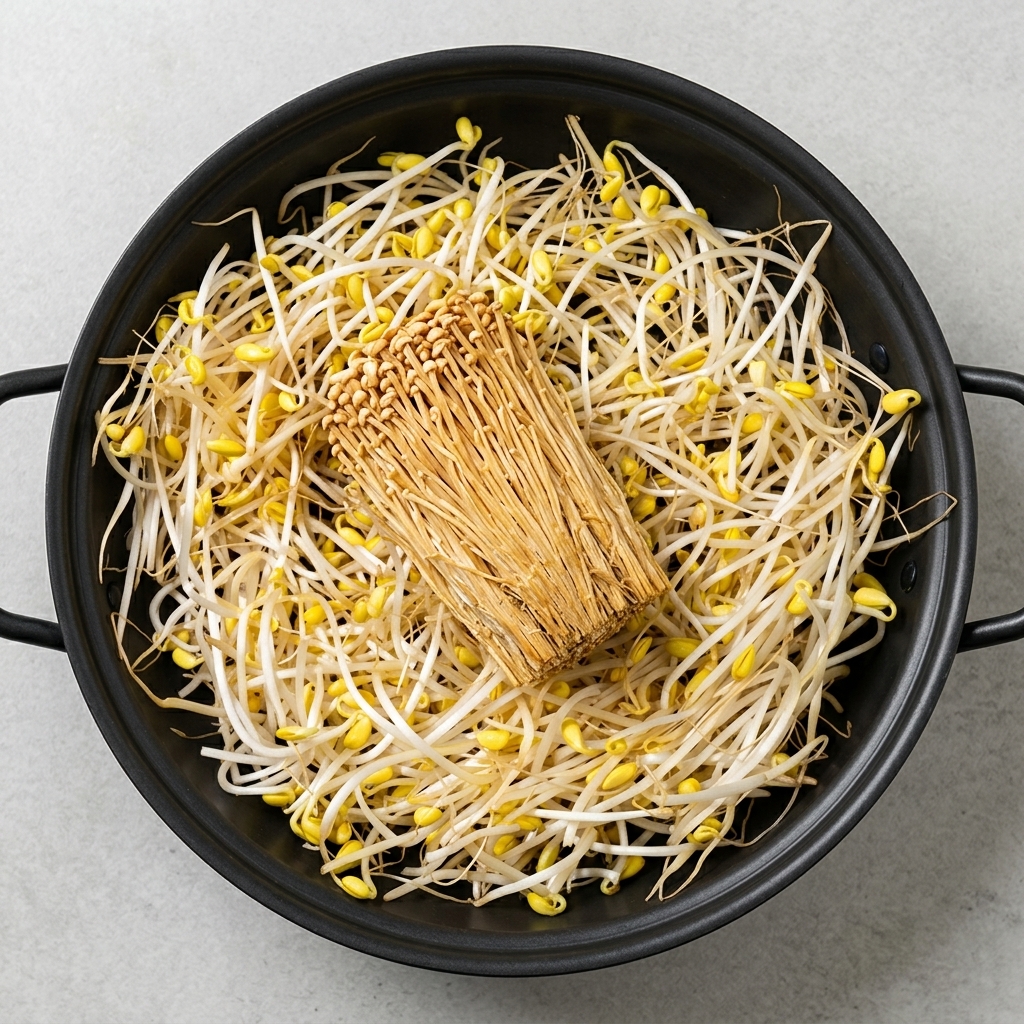 Eine große Auswahl an vorbereiteten Zutaten wie Bohnensprossen, Tofu, Enoki-Pilze, Spam und Wurst, ordentlich in einem Topf arrangiert.